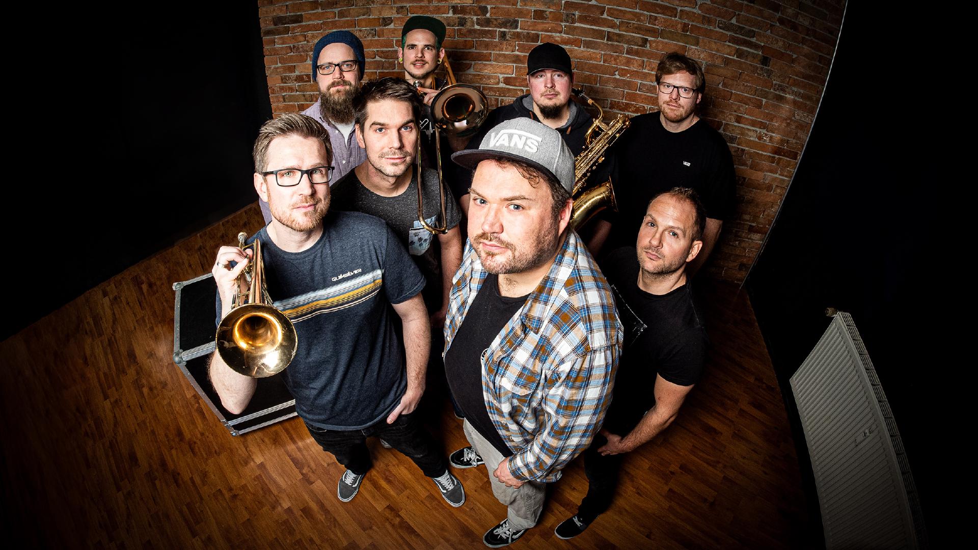 Die achtköpfige Pop-Punk Band mit Bläsern AWESOME SCAMPIS  vor einer Backsteinwand